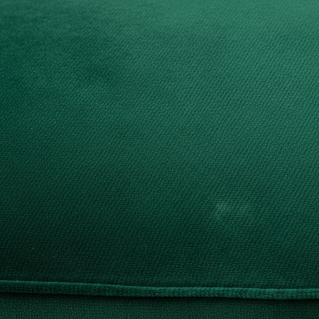 A detailed macro photograph focusing on the luxurious texture of a clean, vibrant microfiber velour sofa in a rich jewel tone like emerald green or deep burgundy. The soft, directional fibers are clearly visible, showcasing the material's plushness and unique sheen. In one small, isolated area, a very subtle, almost translucent stain (e.g., a dried water ring or a faint coffee splash) is barely noticeable amidst the otherwise perfect fabric. This contrast highlights both the beauty and the vulnerability of the velour, inviting a solution. The lighting is soft and highlights the fabric's delicate nap.